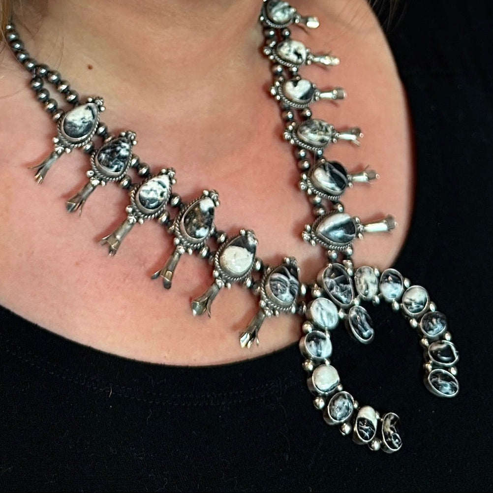 A smiling woman wearing a silver-toned Native American style necklace and matching drop earrings with white stones, shown in a close-up portrait.